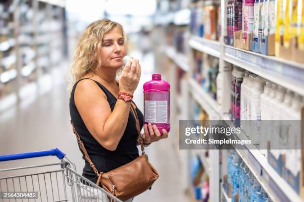 an adult customer smells fabric softener in a supermarket. - fabric softener stock pictures, royalty-free photos & images