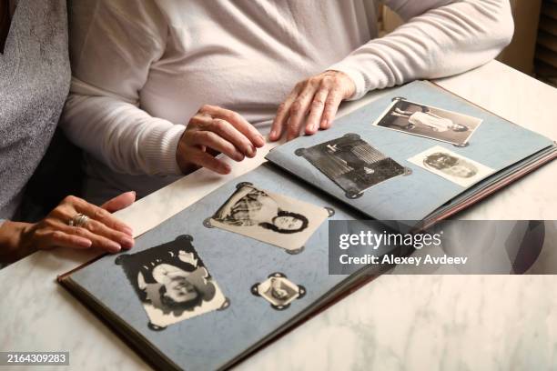 couple looking through vintage black and white photo album, nostalgic family memories - scrapbook stock pictures, royalty-free photos & images