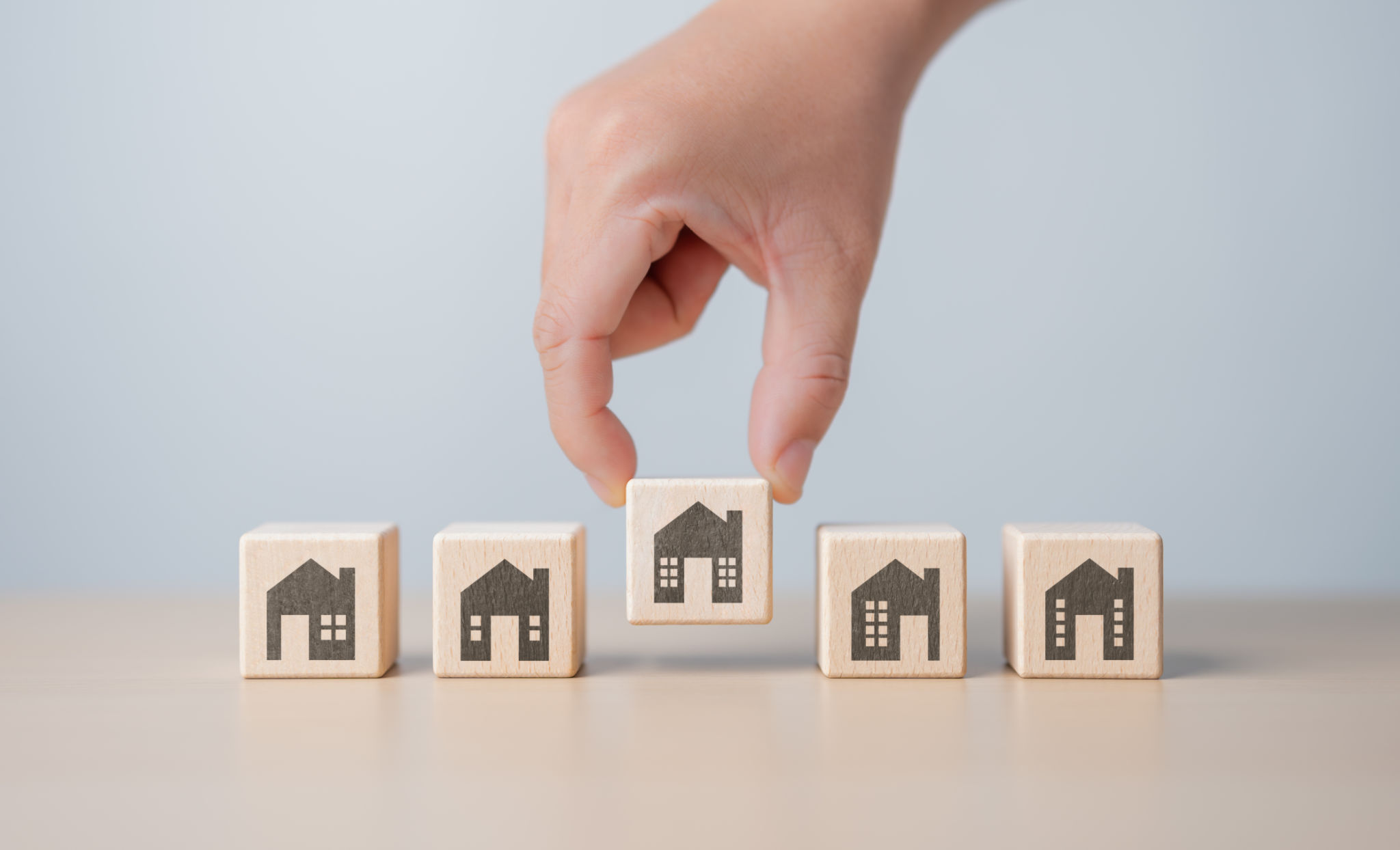 Real estate management, Property, Asset investment concept. Hand picking wooden cube block with house icon from others. Family makes the best decision when choosing the housing you truly want. Real estate management, Property, Asset investment concept. Hand picking wooden cube block with house icon from others. Family makes the best decision when choosing the housing you truly want.