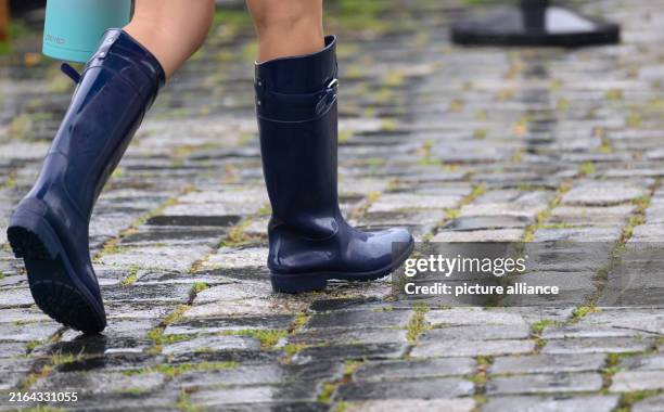 August 2024, Saxony, Dresden: A woman walks across Neumarkt in the rain wearing rubber boots. Photo: Robert Michael/dpa