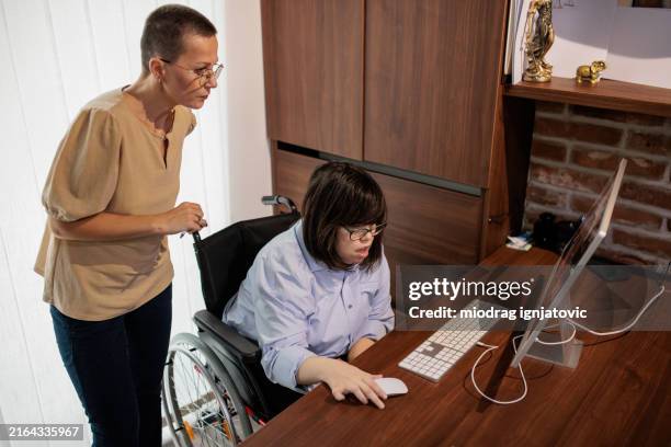 woman assisting a colleague with work on a computer - disability computer stock pictures, royalty-free photos & images