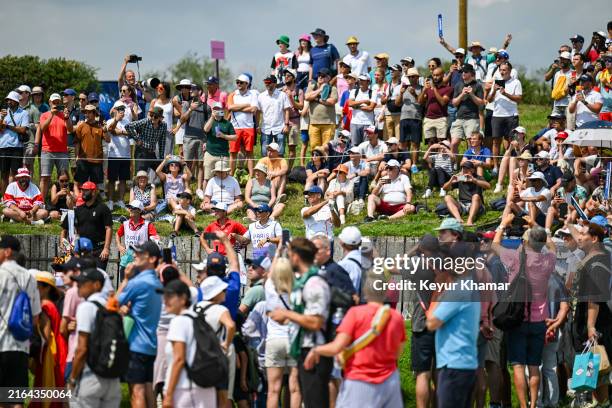Xander Schauffele of Team USA plays a shot from the 17th hole tee as fans watch during the second round of the Olympic men's golf competition on day...