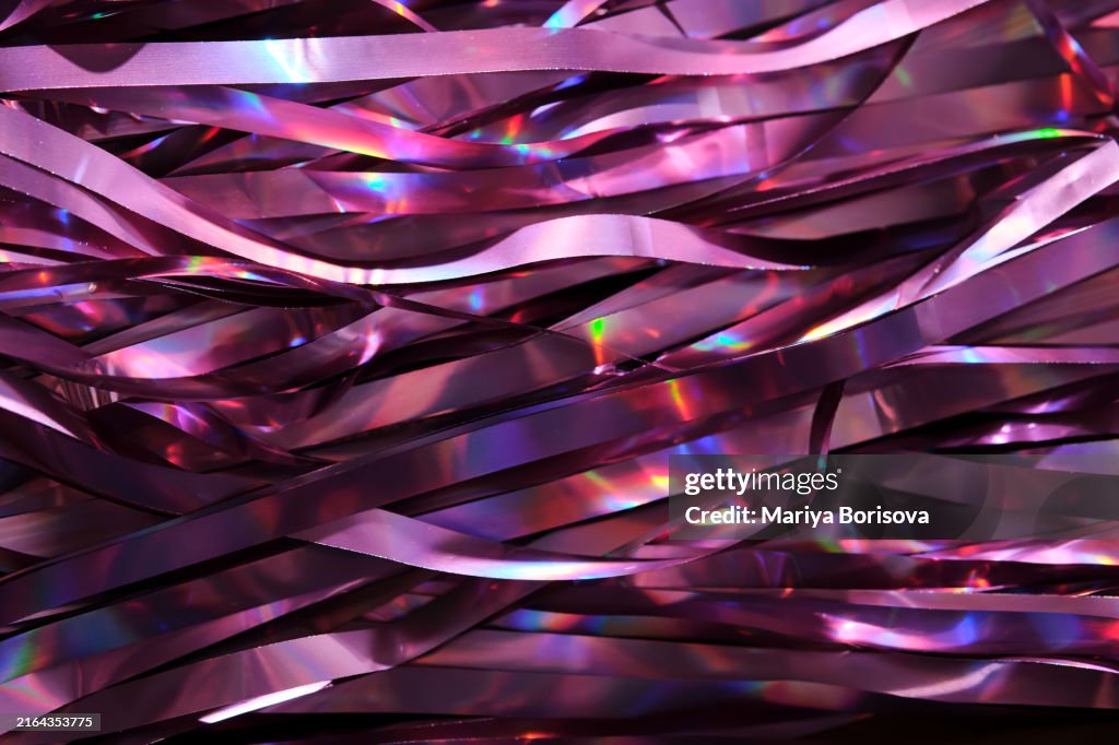 Tinsel with a holographic effect. Festive abstract background with shining bokeh in lilac shades. Perfect for birthdays and Christmas.