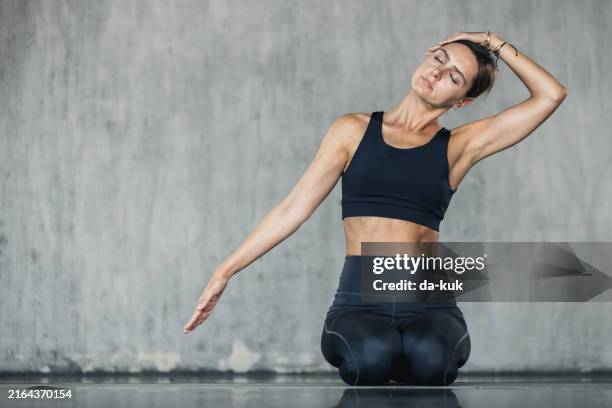 young woman doing neck stretching exercise. stretching and relaxation to improve strength and tone. healthy lifestyle and wellbeing background - hals stock-fotos und bilder