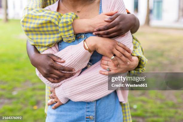 hands of female friends hugging woman from behind at park - three people stock pictures, royalty-free photos & images