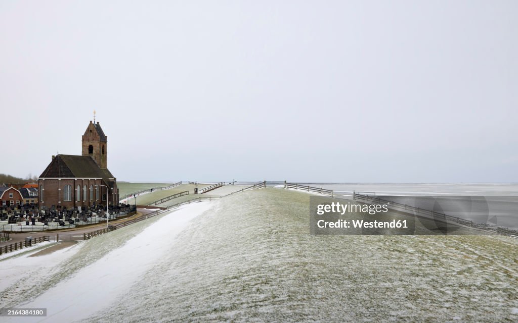 Building near snow and Wadden Sea under clear sky