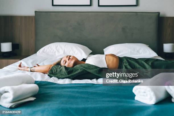sleep tourism. happy woman tourist flopped on the bed in the hotel room - one young woman only stock pictures, royalty-free photos & images