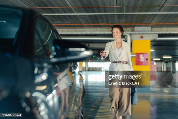 businesswoman opening car door in parking garage - parking stock pictures, royalty-free photos & images
