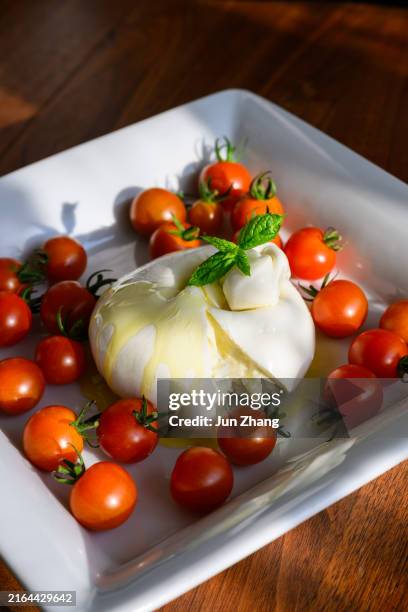 la burrata e i pomodorini maturano sul piatto da portata alla luce del sole del tardo pomeriggio - bufalo indiano foto e immagini stock