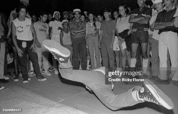 Watched by an audience, an unidentified breakdancer spins on a cardboard surface during a dance battle in the 52 Park public park in the Bronx, New...