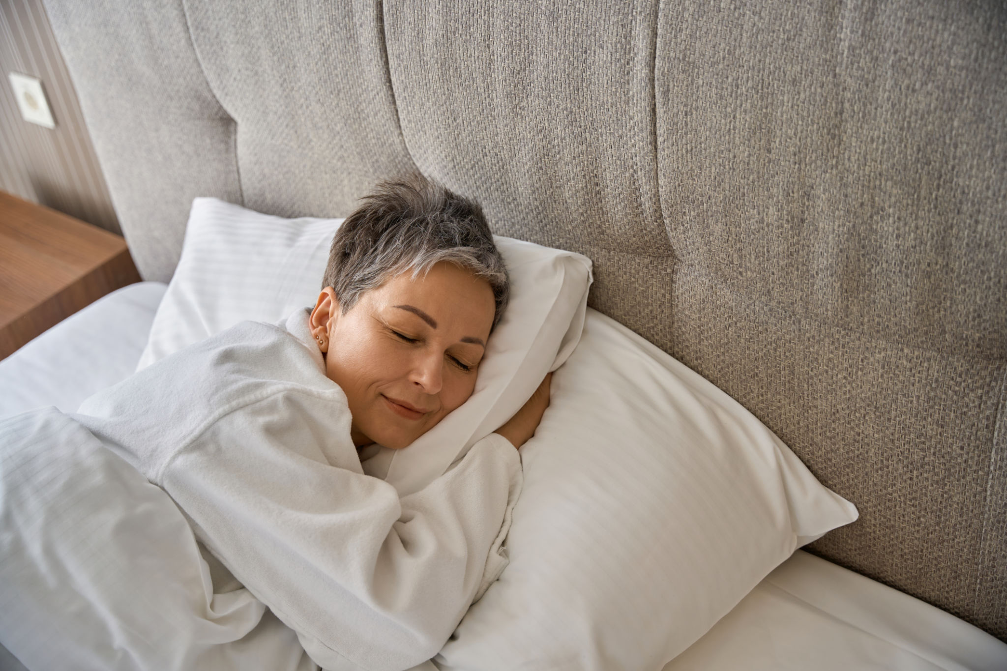 Adult lady in bathrobe resting in hotel room while sleeping Adult lady in bathrobe resting in hotel room while sleeping