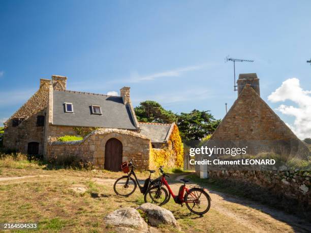 view of three traditional breton stone houses on a hiking trail of the île de bréhat (ile de brehat - brehat island) with bikes in front of them, cotes-d'armor - bretagne (brittany), western france. - cottage stock pictures, royalty-free photos & images
