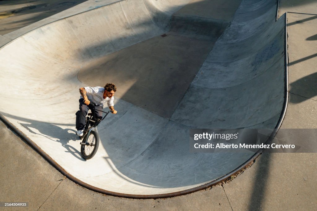 Young man riding his bmx bike on the ramps and bowls of a skatepark