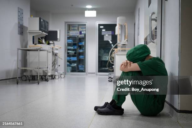 healthcare worker sitting on the floor with stress and sadness after failed operation (or failed surgery) in hospital. - burnout imagens e fotografias de stock