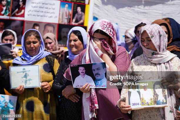 Iraqi Yazidi women cry as they hold pictures of their victims and missing relatives during a ceremony in Chamishko camp, in the Kurdistan Region of...
