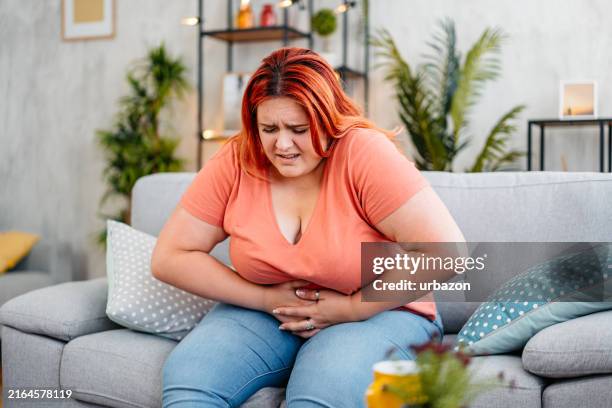 junge frau mit bauchschmerzen zu hause - diarrhö stock-fotos und bilder