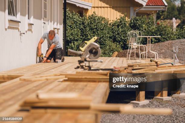 man building a wooden patio deck outdoors in his garden - patio stock pictures, royalty-free photos & images