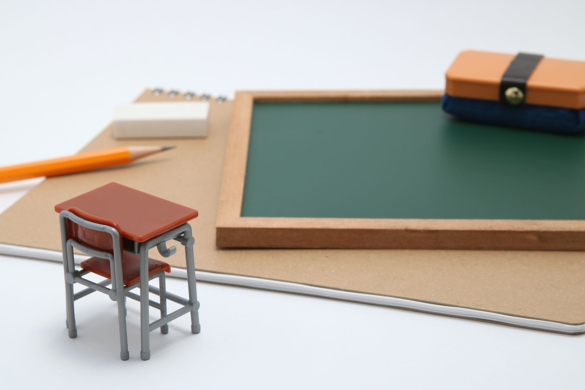 Close-Up Of Small Desk By Book And Chalkboard Over White Background Close-Up Of Small Desk By Book And Chalkboard Over White Background
