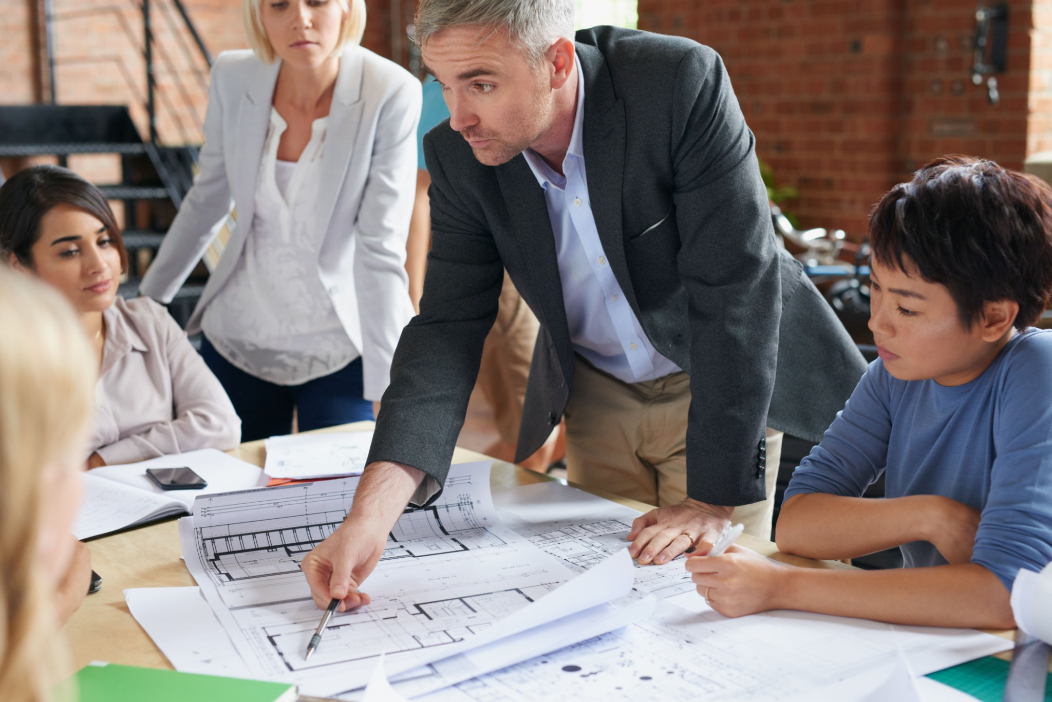 Shot of a group of architects working with blueprints in an office Shot of a group of architects working with blueprints in an office