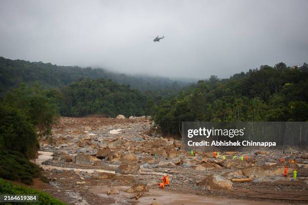 Rescue personnel look for survivors through debris as an Indian Air Force helicopter flies overhead at the site of the landslide on July 31, 2024 in...