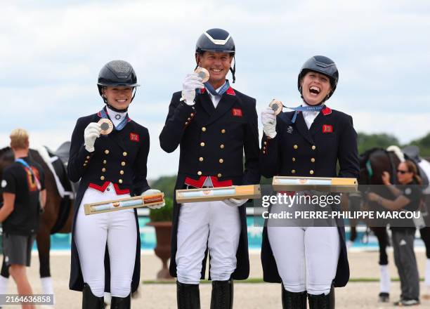 Britain's Charlotte Fry , Britain's Carl Hester and Britain's Becky Moody celebrate their bronze medal on the podium after the equestrian's dressage...