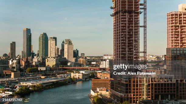 new residential towers' construction on the waterfront in greenpoint, brooklyn with towers of long island city over the newtown creec. - greenpoint brooklyn stock pictures, royalty-free photos & images
