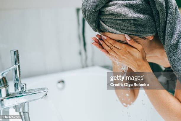 skincare routine and washing. woman in bath towel washes her face and looks after her skin early in the morning - hyperpigmentation stockfoto's en -beelden