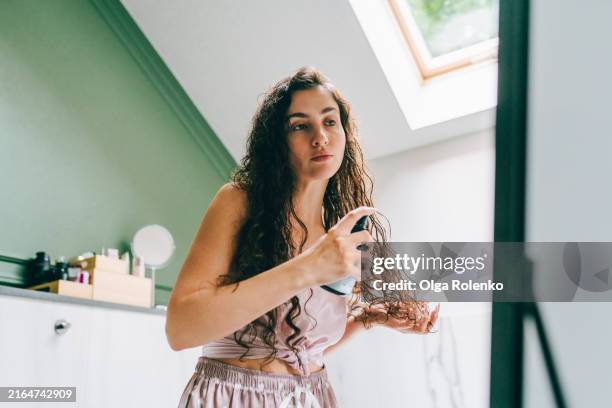 curly hair oil application: woman applies oil for curly method in hair care and length restoration at home - beauté et soins du corps photos et images de collection
