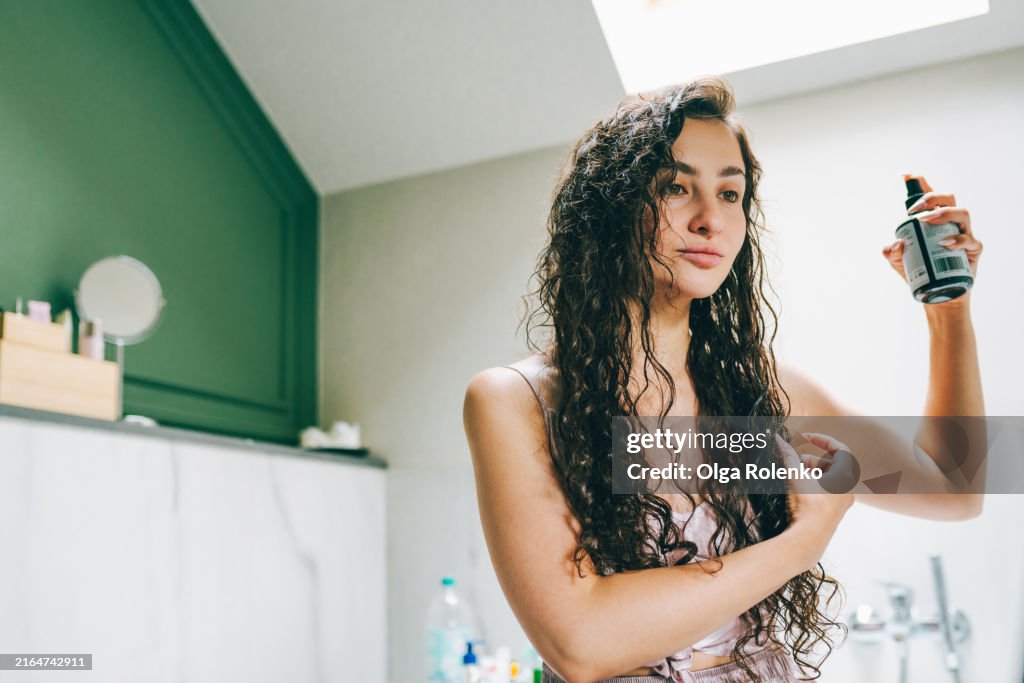 Curly hair care: woman uses oil for curly method to restore hair length at home