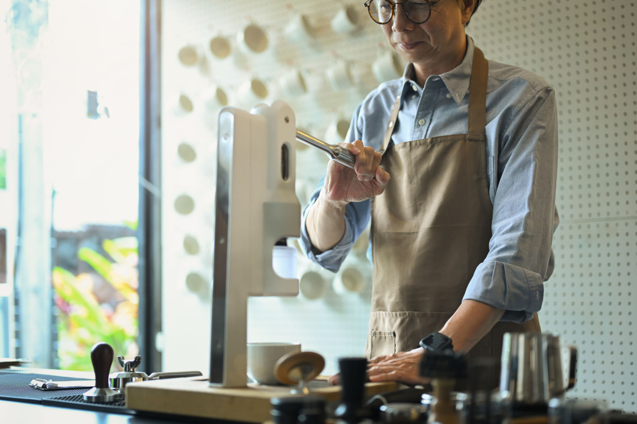 Smiling wearing apron preparing coffee for customers at his cafe counter Smiling wearing apron preparing coffee for customers at his cafe counter