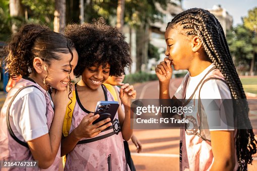Athlete boy showing mobile phone to friends on a running track Athlete boy showing mobile phone to friends on a running track