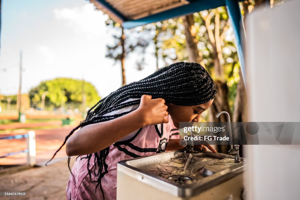 Athlete girl drinking water on a running track