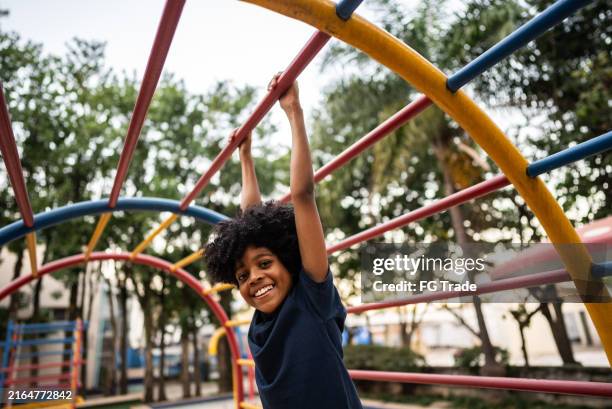 ritratto di un ragazzo che gioca nella palestra della giungla in un parco giochi - giochi per bambini foto e immagini stock