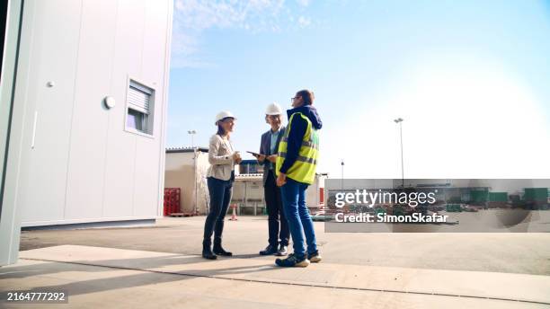 business professionals planning while standing outside storage room against sky - reflective clothing stock pictures, royalty-free photos & images