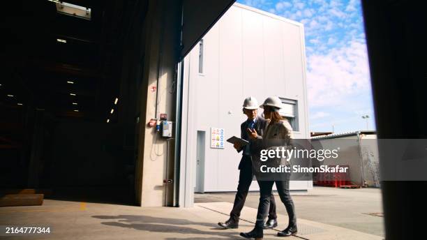 colleagues discussing over digital tablet while entering distribution warehouse - factory door stock pictures, royalty-free photos & images