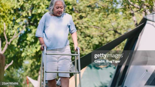 senior female patient using mobility walker in public park. - flácido imagens e fotografias de stock