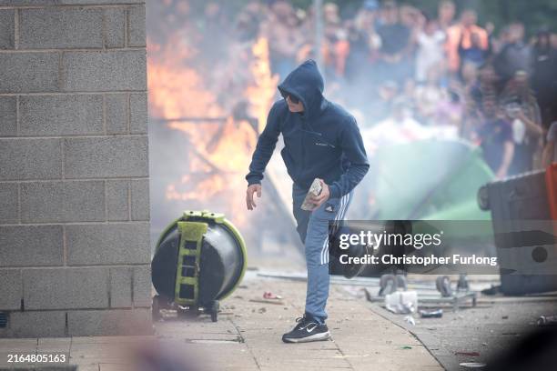 An anti-migration protester prepares to throw a piece of concrete during riots outside of the Holiday Inn Express in Manvers, which is being used as...