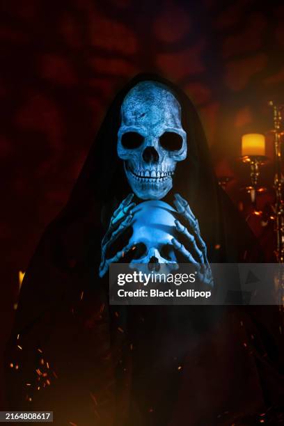 scary grim reaper looking at the camera, holding a human skull. - grim reaper stock pictures, royalty-free photos & images