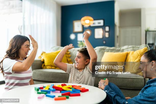 lesbian family with adopted son playing games at home - foster care stock pictures, royalty-free photos & images