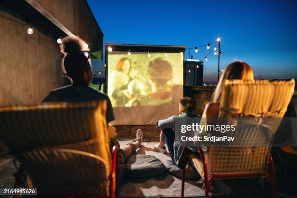 unrecognizable multiracial female and male friends, having an movie night on rooftop - projection equipment stock pictures, royalty-free photos & images