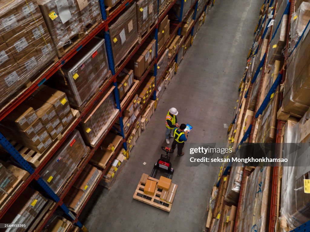 Top view of warehouse worker using laptop to check location of goods.