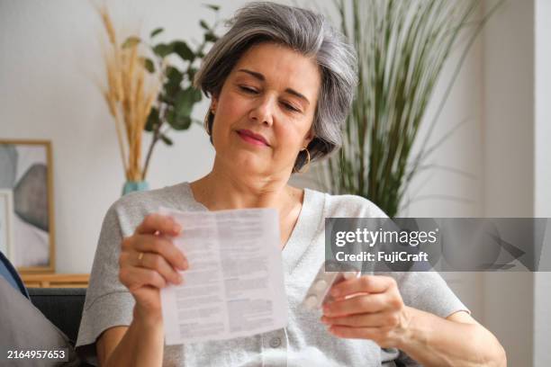 senior woman reading medical instructions before taking pills at home - instructions stock pictures, royalty-free photos & images