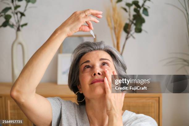mature woman applying eye drops at home - dry stock pictures, royalty-free photos & images