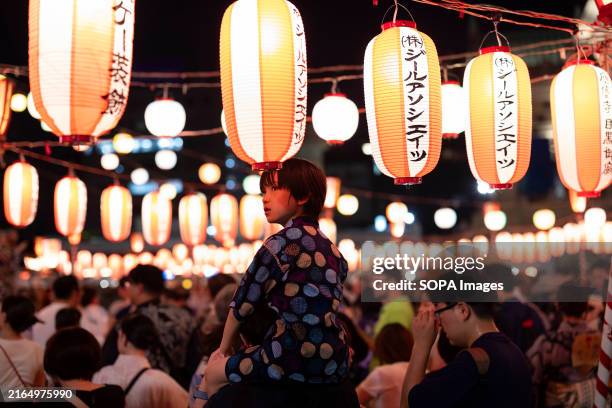 Boy sits on his fathers shoulders during Tsukiji Honganji Bon Dance Festival. Bon Odori dance festivals are held across Japan all summer long....