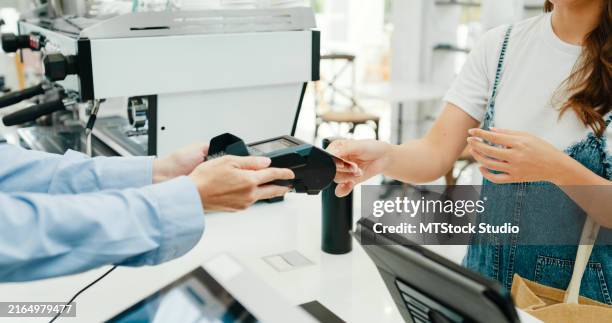 closeup of senior asian female entrepreneurs processing contactless credit card payment for customer in her modern cafe. small business owner. - check bildbanksfoton och bilder