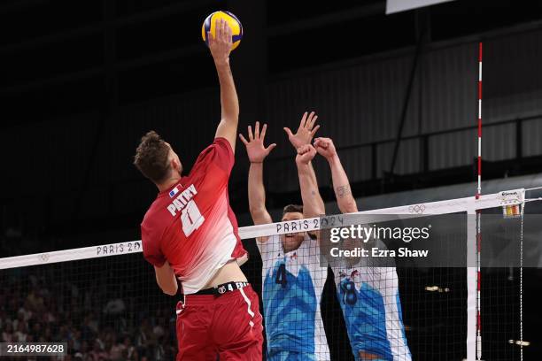 Jean Patry of Team France attacks the net against Jan Kozamernik and Klemen Cebulj of Team Slovenia during the Men's Preliminary Round - Pool A match...