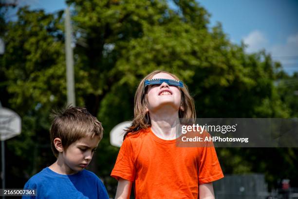 non-binary child and brother watching solar eclipse with special glasses - eclipse people stock pictures, royalty-free photos & images