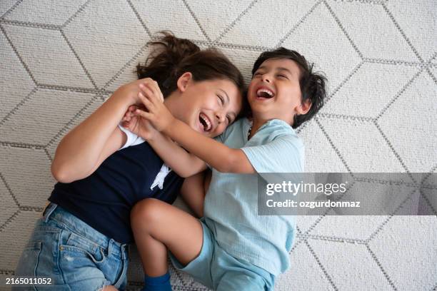 fratelli che giocano sul tappeto sul pavimento - famiglia con due figli foto e immagini stock
