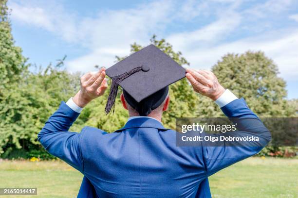 rear view of a man holding a graduation hat with his hands - borla fotografías e imágenes de stock