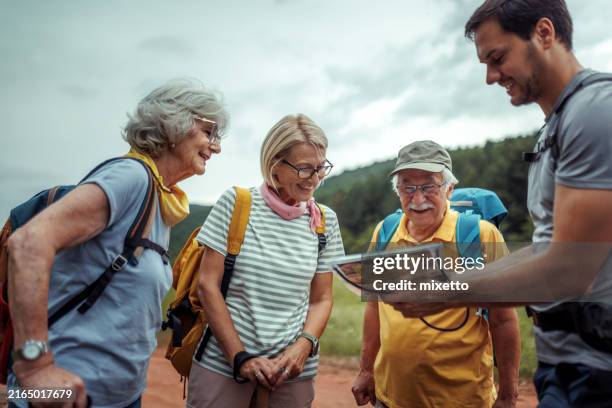 groupe de randonneurs seniors souriant et discutant avec leur guide - guide photos et images de collection